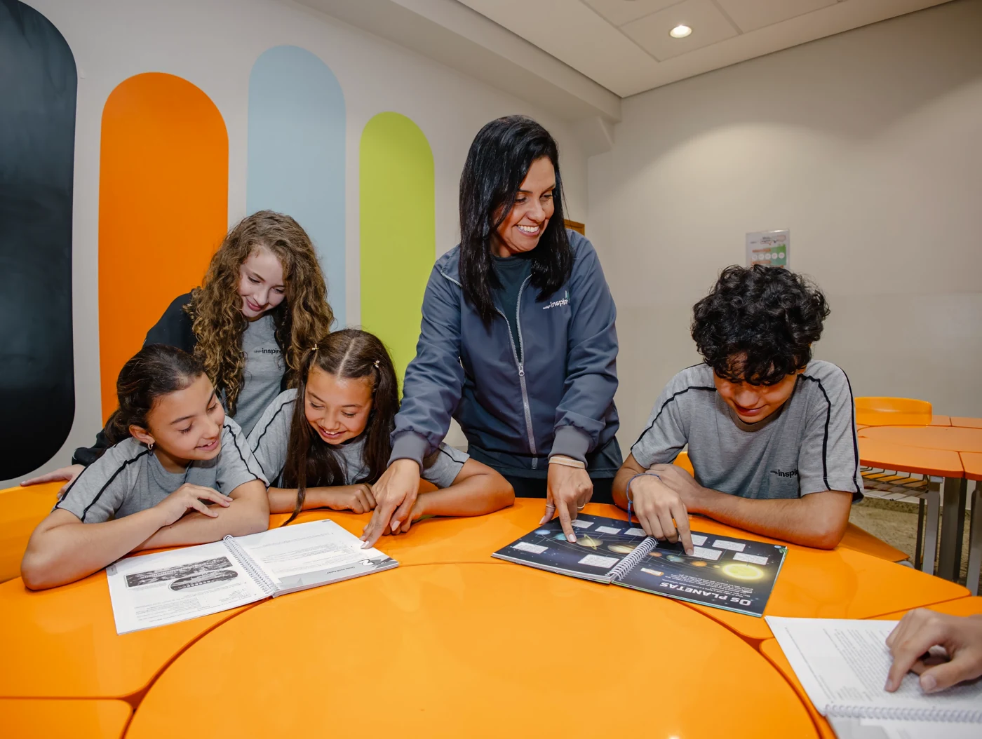 Alunos estudando juntos com orientação de uma educadora