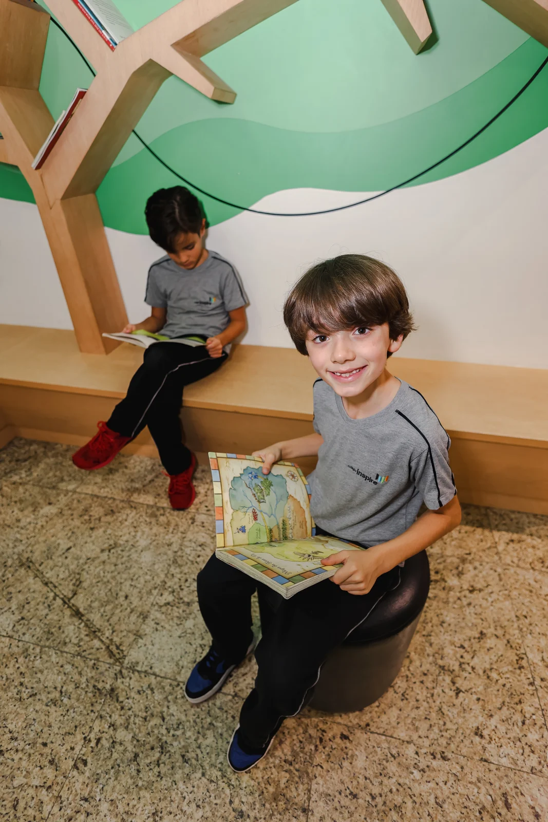 Alunos com livros no espaço de leitura do colégio