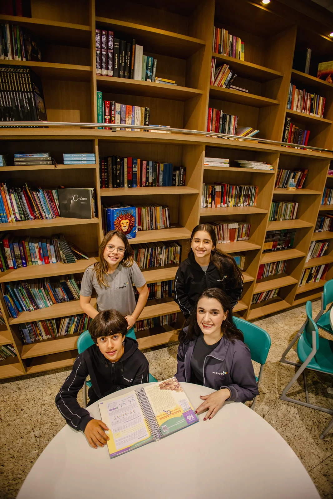 Grupo de alunos reunido em uma atividade de leitura na biblioteca