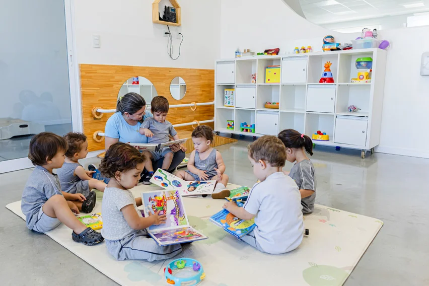 Professora e crianças lendo juntas em sala de aula