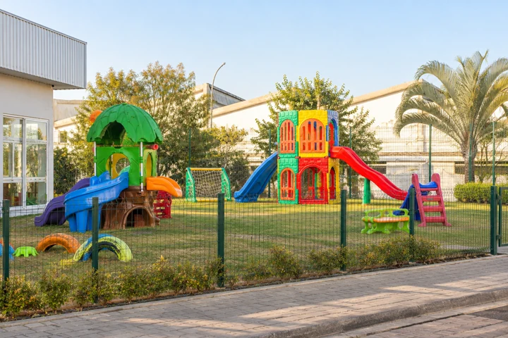 Playground externo com brinquedos coloridos, escorregadores e área verde