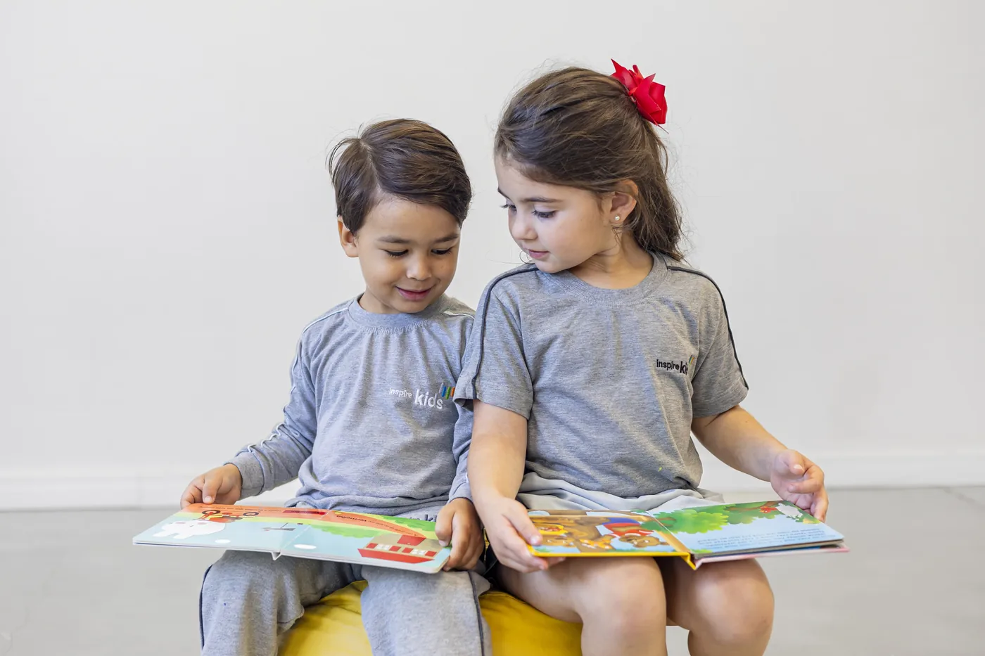 Duas crianças do Inspire Kids lendo um livro juntas